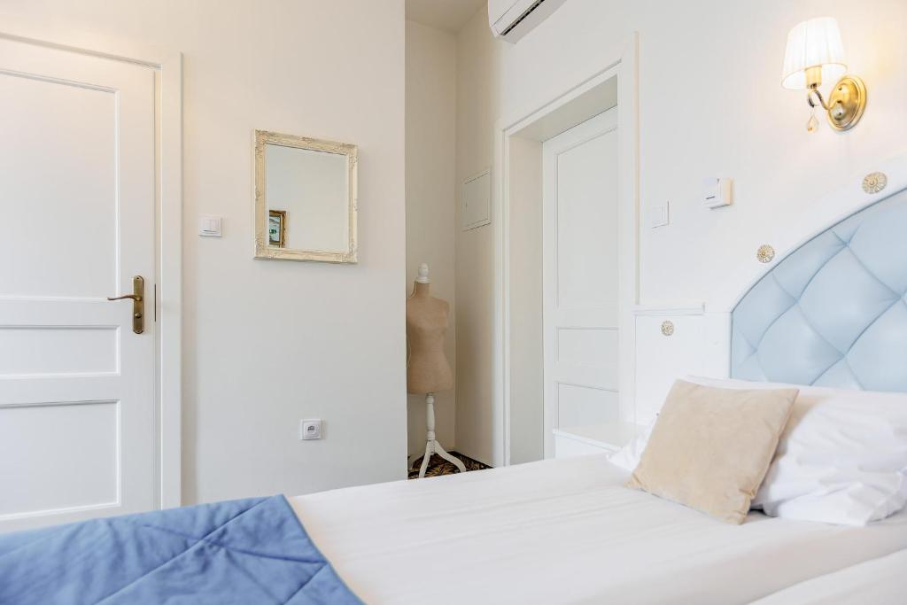 Single bed corner with pale blue tufted headboard, beige pillow, decorative mannequin and wall mirror.