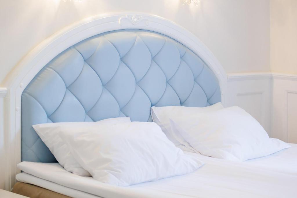 Double bed with pale blue tufted headboard and neatly arranged white pillows.