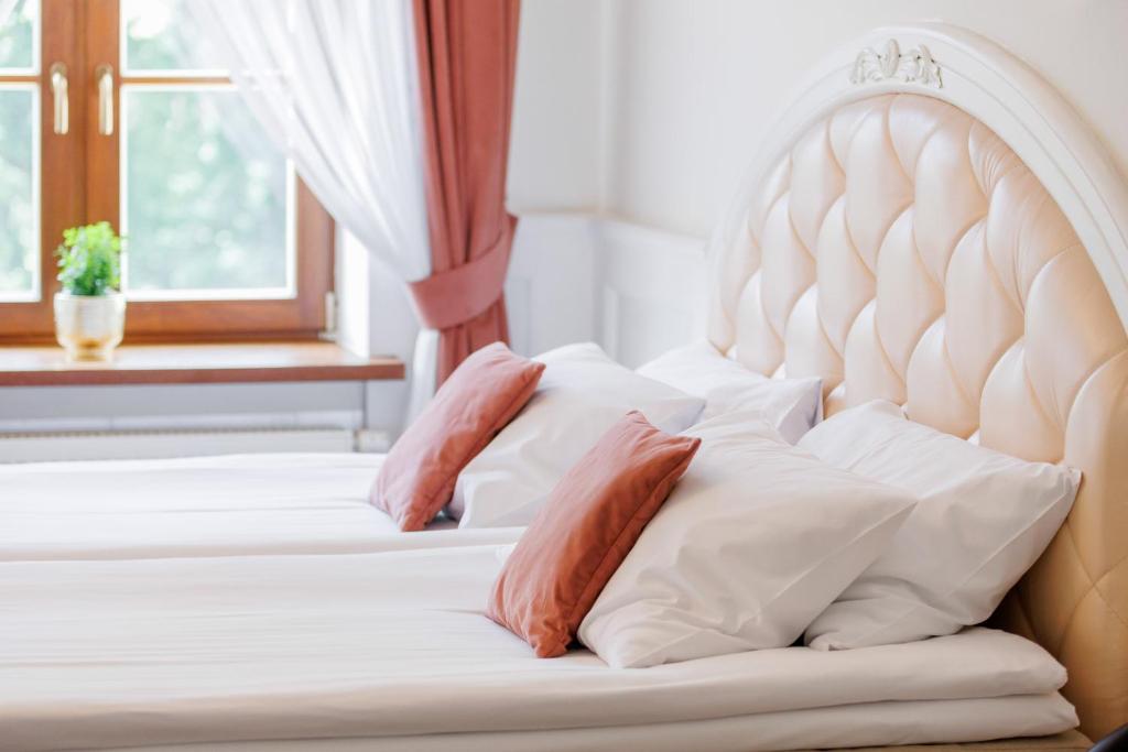Cropped view of bed with tufted cream headboard, white pillows and coral accent cushions.