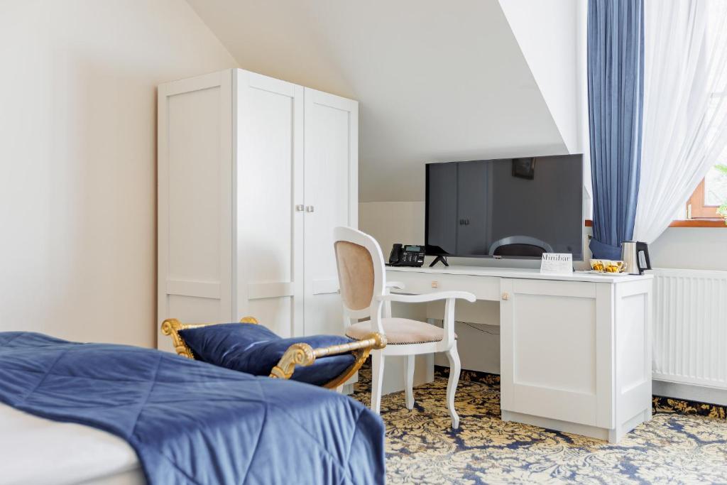 Bright attic bedroom with blue bedspread, white desk and TV, wardrobe, elegant chair.