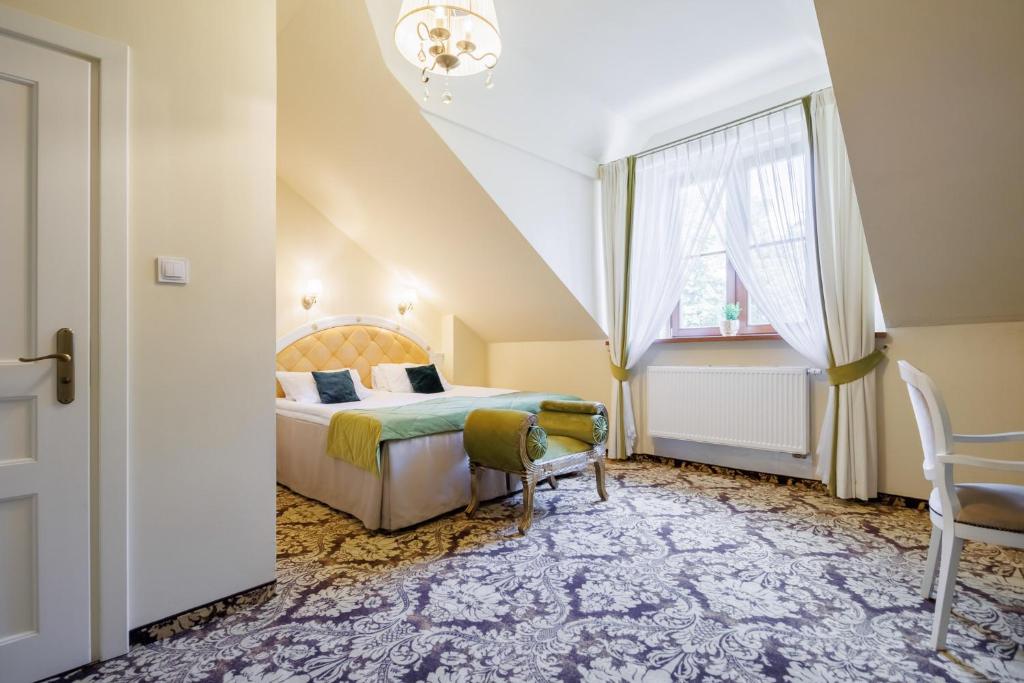 Bright attic bedroom with double bed, green bench, patterned carpet and sunlit window.