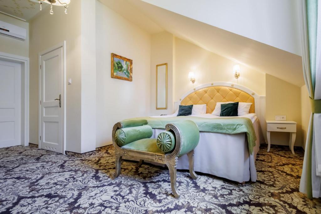 Cozy sloped-ceiling bedroom with tufted headboard, green bench at bed foot, ornate carpet.