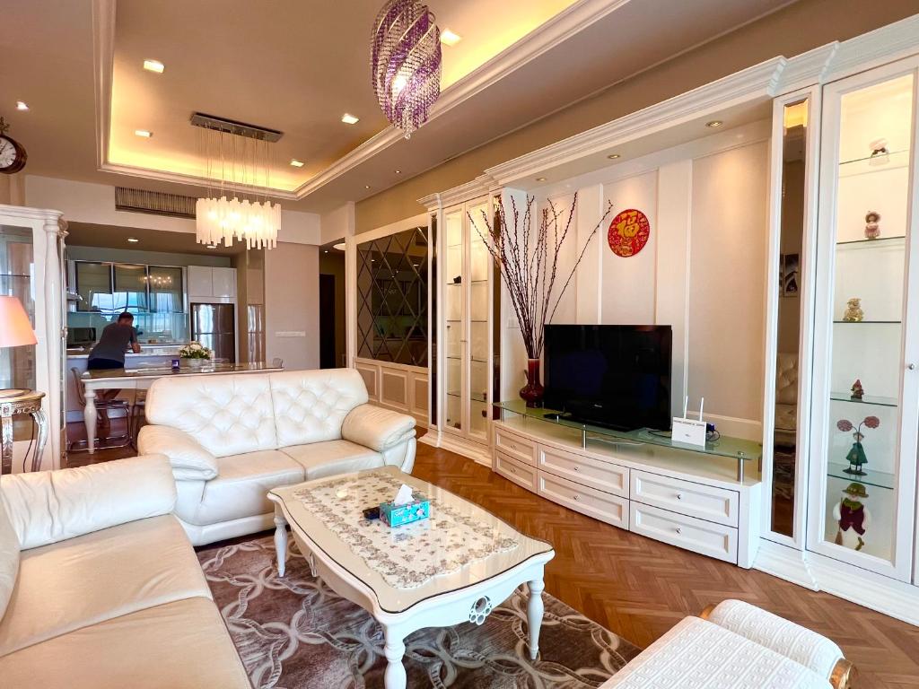 a living room with white furniture and a tv at Luxury Seaview Family Suite at Straits Quay in Tanjong Tokong
