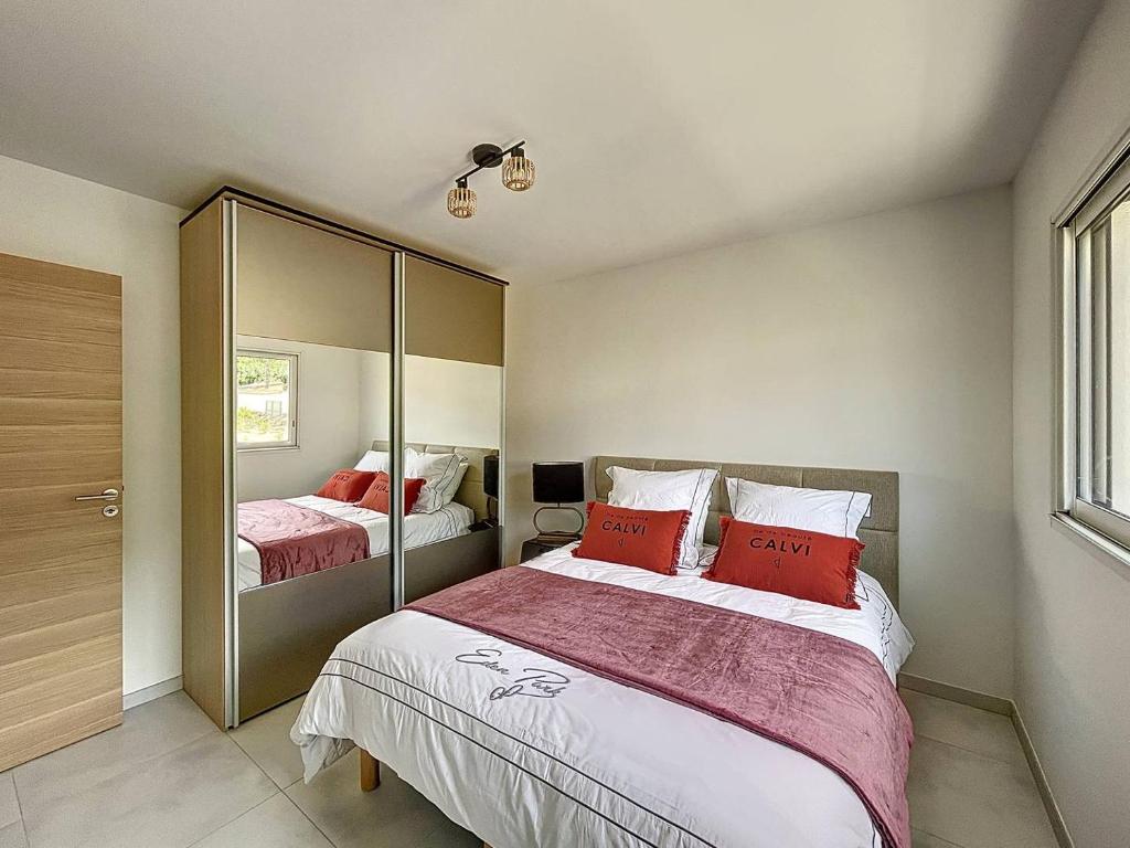 a bedroom with two beds with red pillows at Appartement avec vue panoramique sur la mer in Calvi