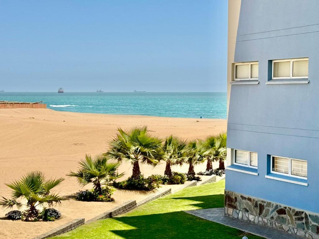 a building next to a beach with palm trees at Ocean Dream Sunset Sails in Swakopmund