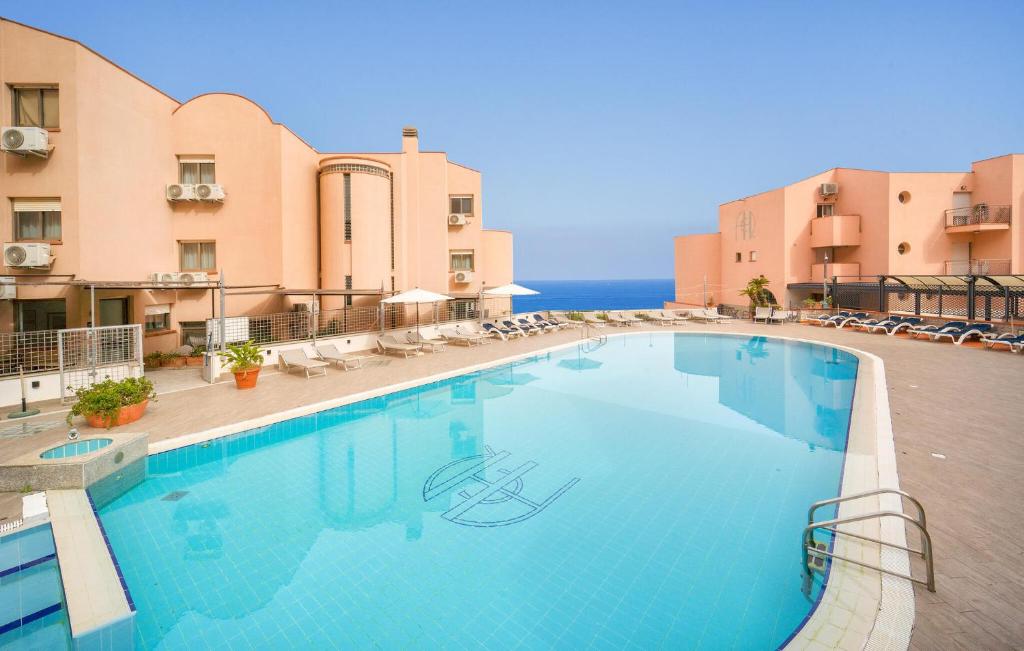 a swimming pool with chairs and the ocean in the background at Mono 2 in Lido di Mondello