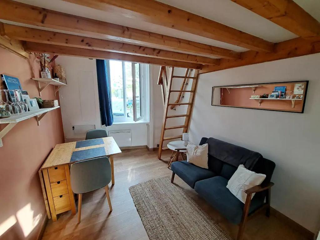 un salon avec un canapé bleu et une table dans l'établissement Charmant studio gare intra-muros, à Saint-Malo