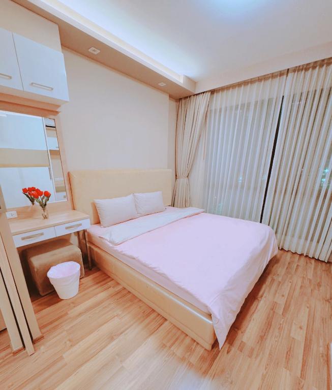 a bedroom with a large white bed and a window at CBP treasure swimming condo in Chiang Mai