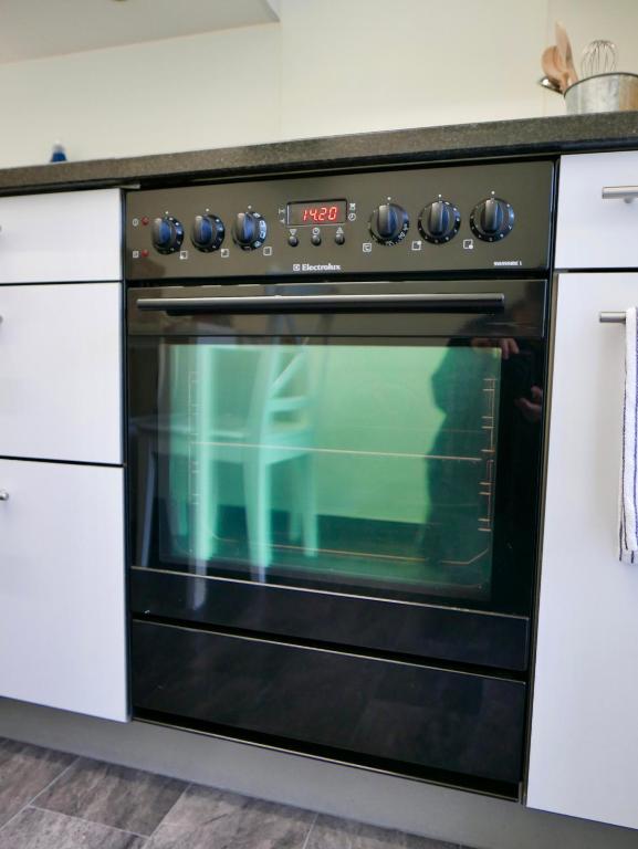 a black oven in a kitchen with white cabinets at Gemütliche Wohnung Nähe Uni in Basel