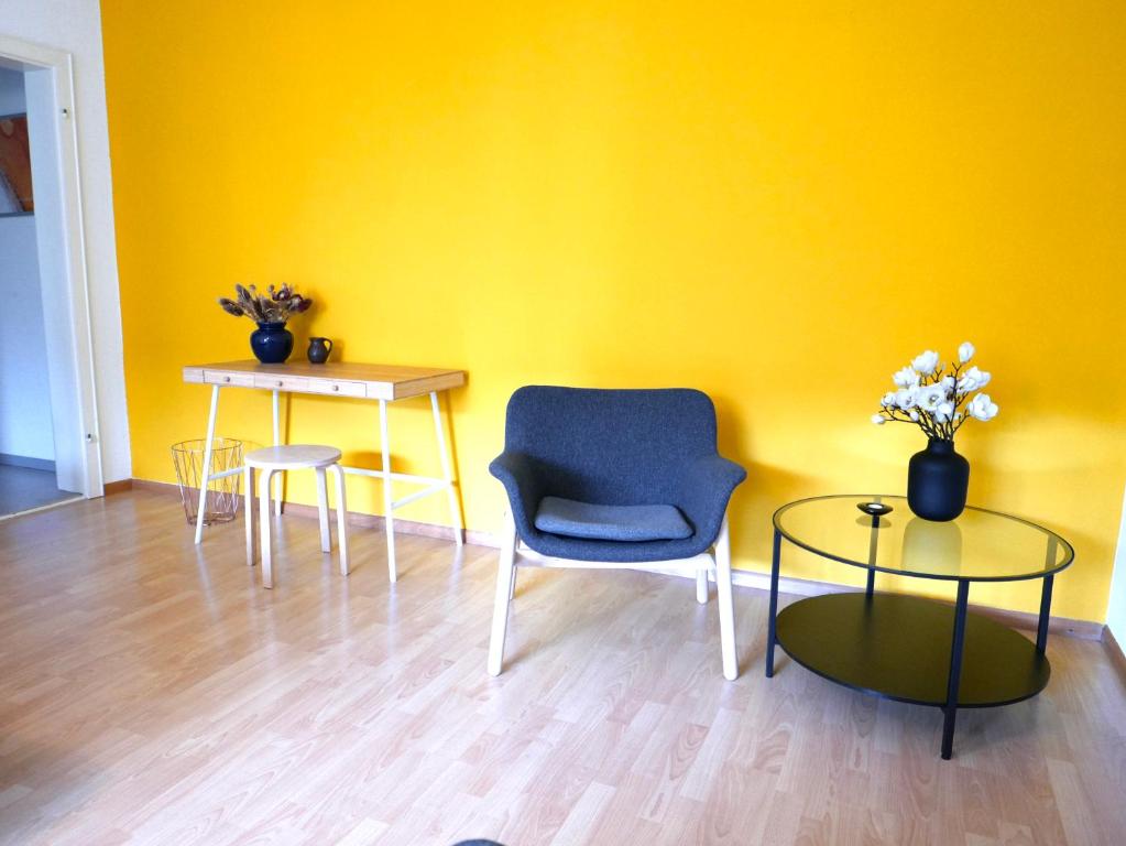 a yellow room with a chair and a table at Gemütliche Wohnung Nähe Uni in Basel