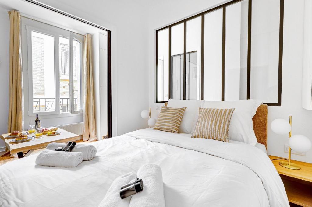 un grand lit blanc dans une pièce avec des fenêtres dans l'établissement Suite Javel - Appartement à Paris, à Paris