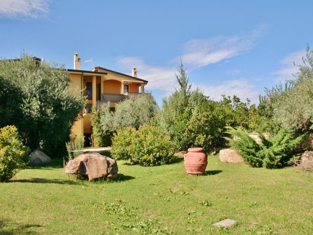 un patio con una casa y algunas plantas y rocas en Villa Tanit, en Lotzorai