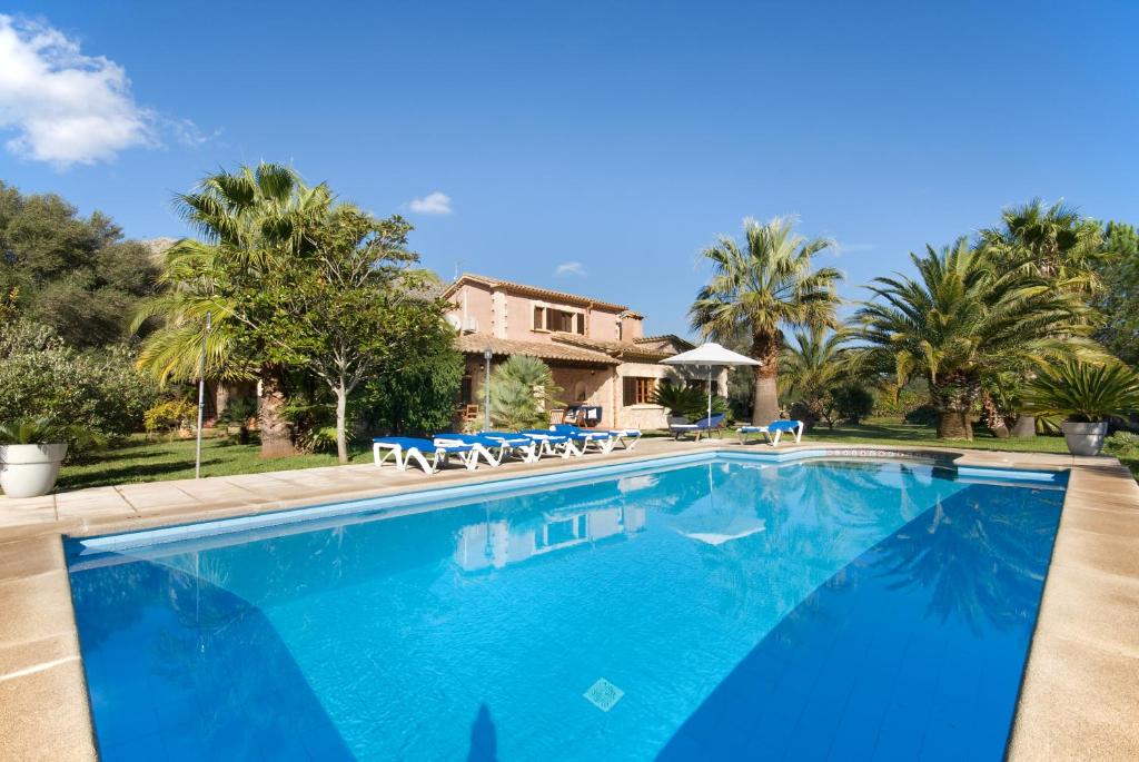 a swimming pool in front of a house with palm trees at Jardí de Papallones in Pollença