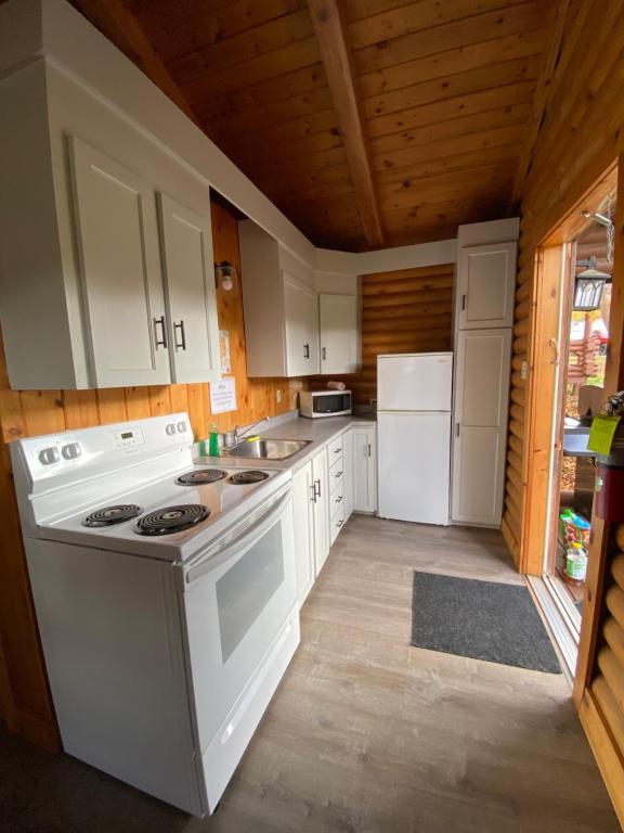 a kitchen with white appliances and a wooden ceiling at Adventures East Cottages and Campground in Baddeck Inlet