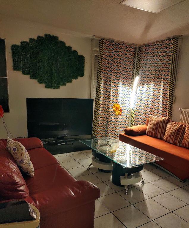 un salon avec un canapé et une table en verre dans l'établissement Appartement T3 proche de Bâle, à Saint-Louis