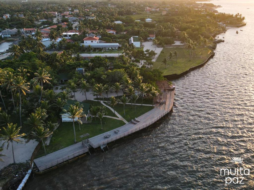 an island with palm trees and a dock in the water at Muita Paz Rooms in Atins