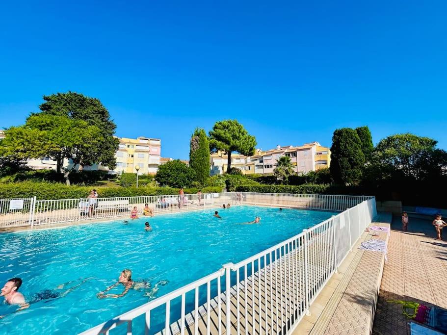 un groupe de personnes nageant dans une piscine dans l'établissement Apt T2 climatisé à 2 min plage du mole avec balcon et piscine, au Cap d'Agde