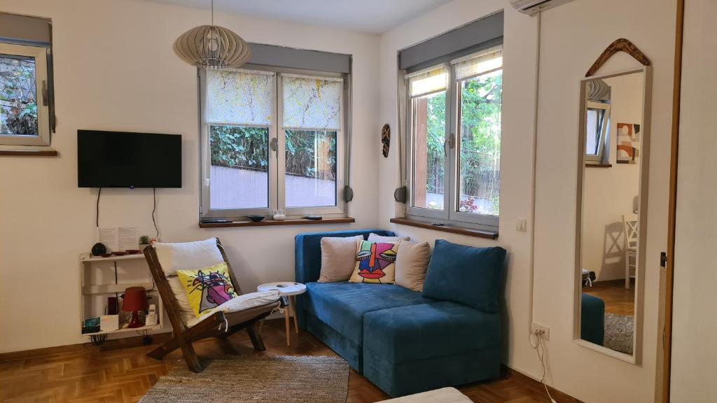 a living room with a blue couch and windows at Apartman BelLe in Belgrade