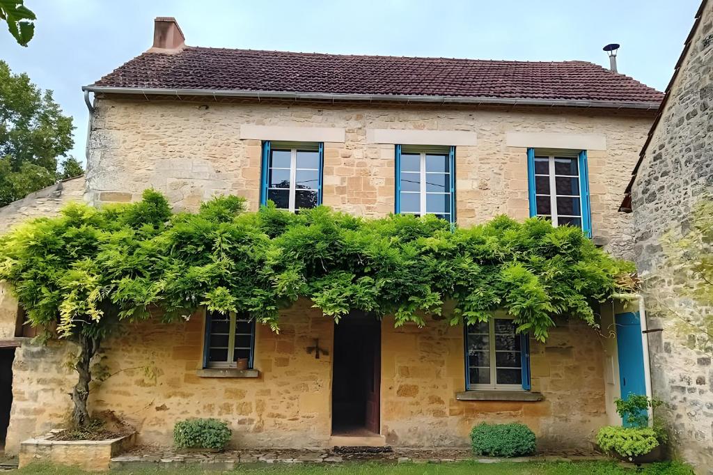 une vieille maison en pierre avec une bande de plantes dans l'établissement La Maison De Carmensac, à Meyrals