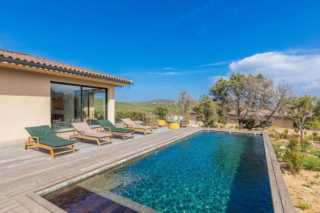 una piscina con sedie e una casa di Villa Paola a Pianottoli-Caldarello