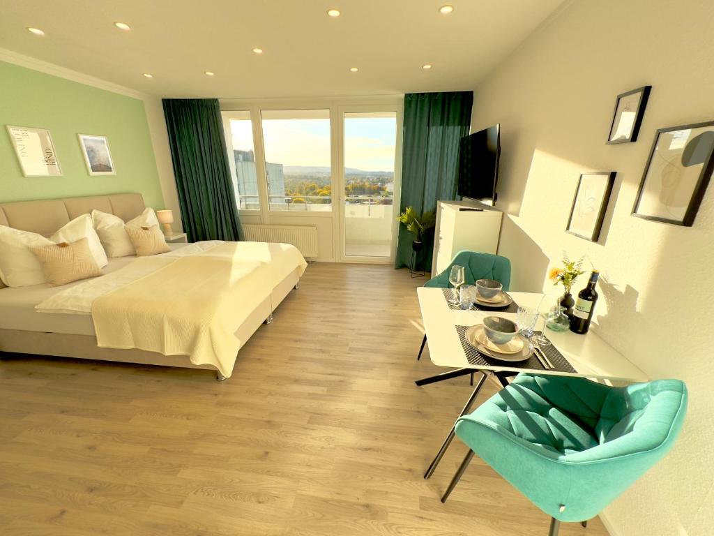 a hotel room with a bed and a table and chairs at M&D Apartments nähe Stadion mit Klimaanlage - Netflix - Küche - Sunset View - Balkon in Kaiserslautern