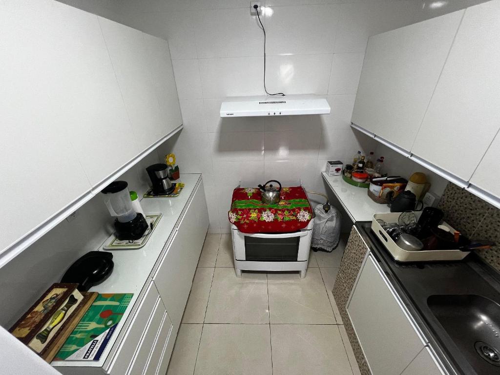 a small kitchen with white cabinets and a stove at Casa aconchegante 2 qtos Centro de Angra dos Reis in Angra dos Reis