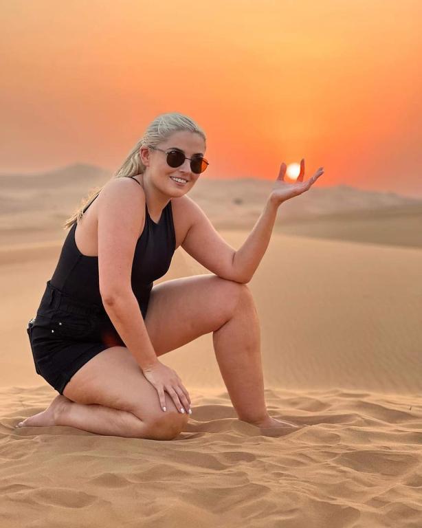 a woman is sitting in the desert holding a candle at Jaisalmer Desert Camp in Sām