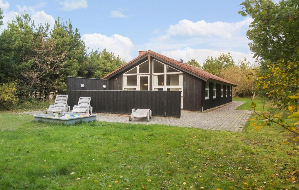 a small house with two chairs and a patio at Nice Home In Blåvand With Sauna in Blåvand