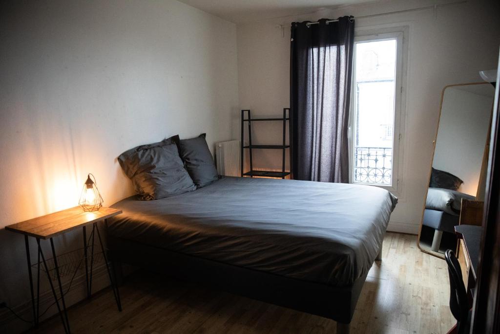 a bedroom with a bed with a lamp and a window at Paris Flea Market Comfy Flat in Saint-Ouen