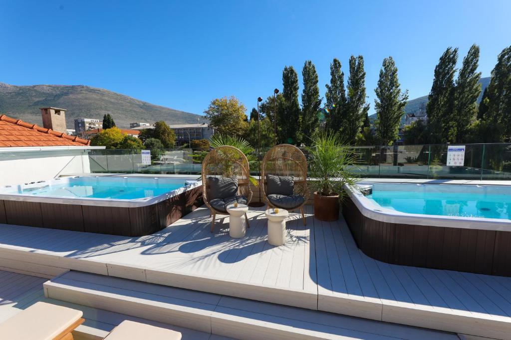 eine Terrasse mit zwei Stühlen und einem Swimmingpool in der Unterkunft Integra Hotel in Trebinje