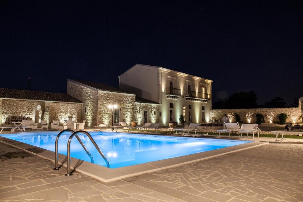 a swimming pool in front of a building at night at Casale 1821 in Ragusa
