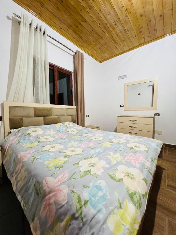 a bedroom with a bed with a floral comforter at Bert-House close to the sea in Lezhë