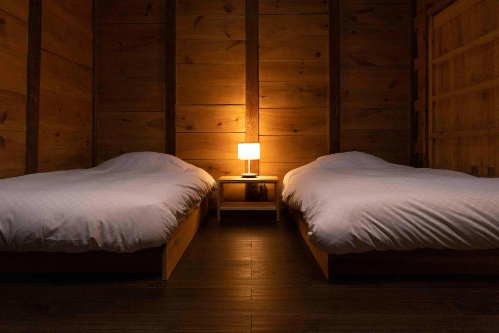 two beds in a room with a lamp on a night stand at Satoyama Villa Honjin - Vacation STAY 17846 in Matsumoto