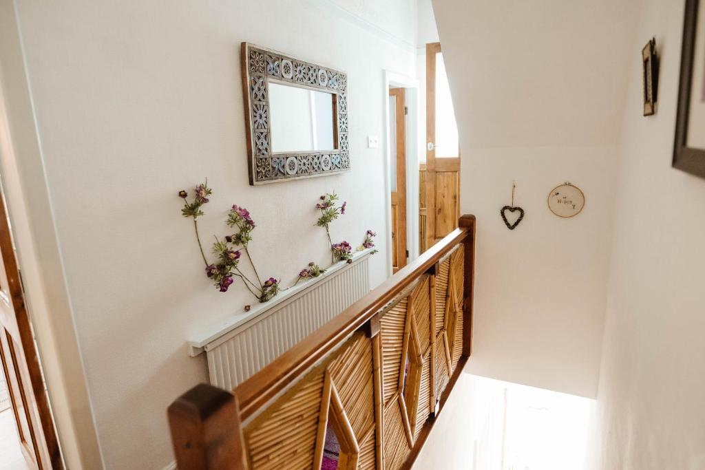 a stairway with flowers on the wall and a mirror at Quirky comfort cottage in Haslingden