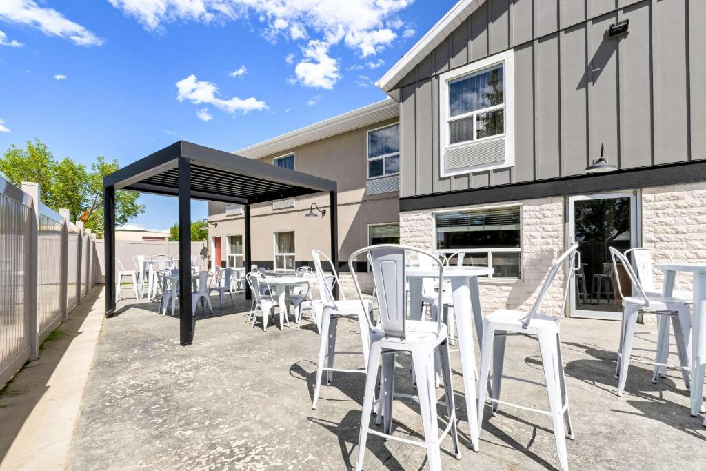 een groep witte stoelen en tafels op een patio bij SureStay Plus Hotel by Best Western Drumheller in Drumheller
