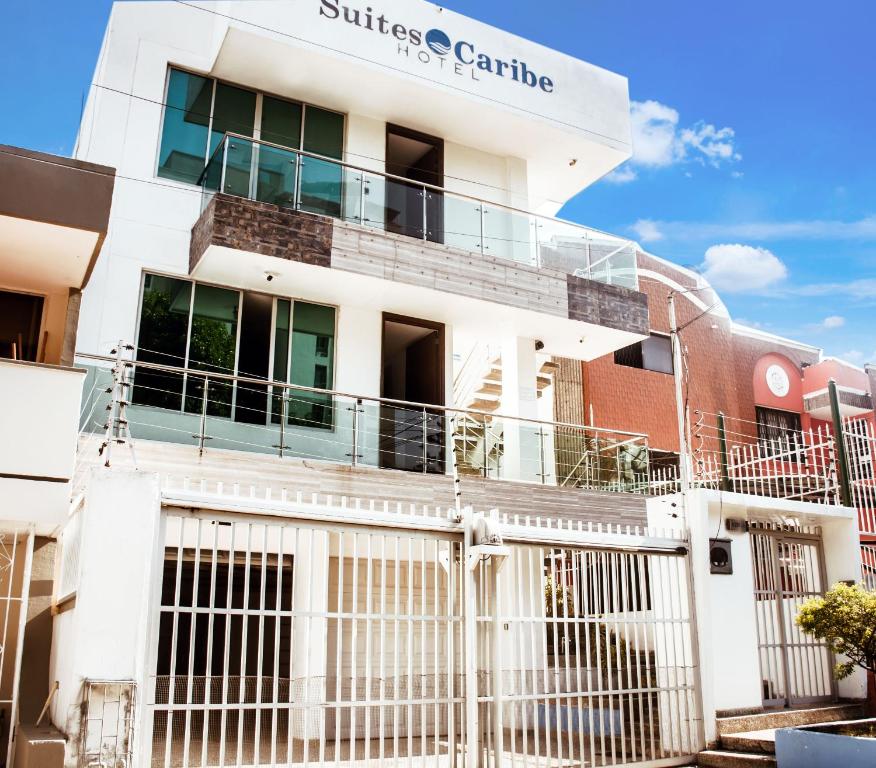 a white building with a fence in front of it at Hotel Suites Caribe in Barranquilla