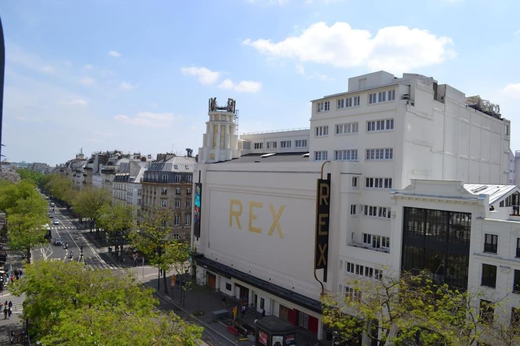 - un grand bâtiment blanc avec un panneau rex dans l'établissement Magnifique appartement, vue Grand Rex, à Paris