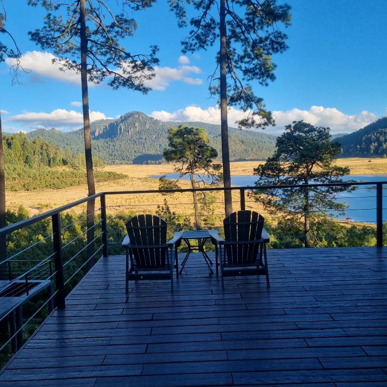 two chairs and a table on a deck with a view at Lobo Glamp in Amanalco de Becerra