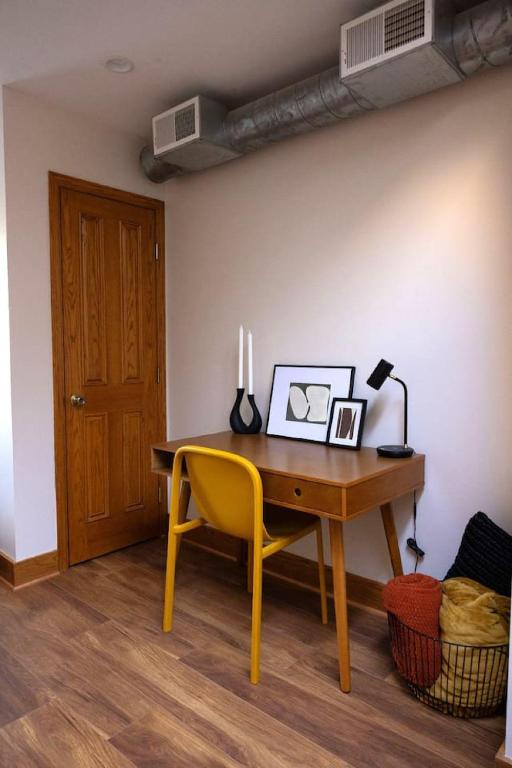 un bureau avec une chaise jaune et une table avec une lampe dans l'établissement Charming and Cozy Studio in DT Northfield, à Northfield
