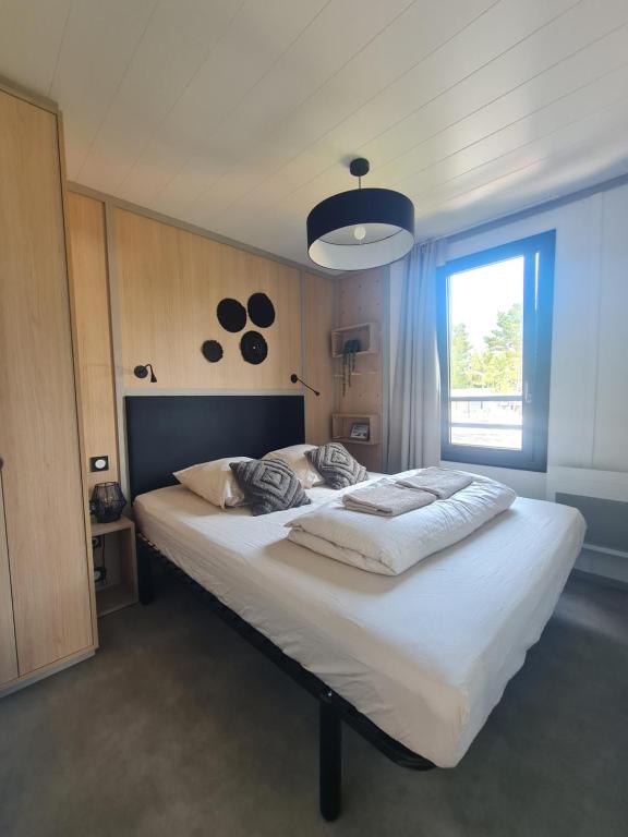 a bedroom with a large white bed with a window at Cottage pour 6 personnes avec piscine couverte et chauffée à 300 m de la mer avec Wi-Fi et climatisé , 3 chambres in Jullouville-les-Pins