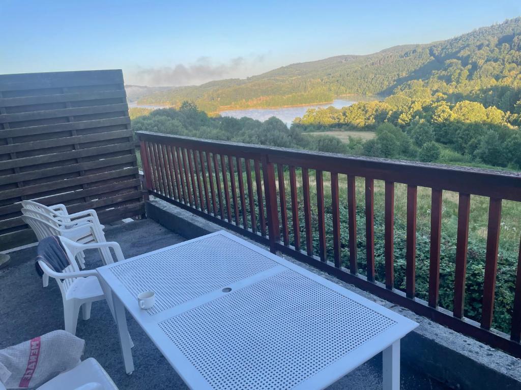een witte tafel en stoelen op een balkon met uitzicht bij Chalet lac de la Raviege vue lac in La Salvetat