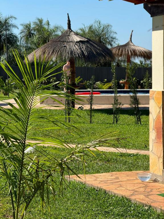 una persona in piedi in un cortile con un ombrellone in erba di Residencia Piri a Piribebuy