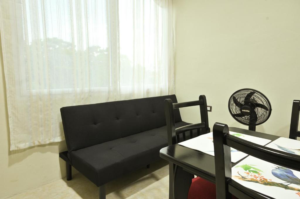 a living room with a black couch and a table at Apartamentos Petenchel, por Aeropuerto Flores Peten no 3 in Santa Elena