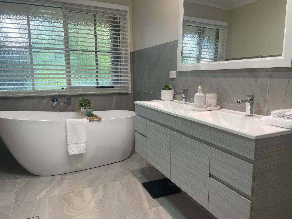 a white bathroom with a tub and a sink at The Old Rose Farm House in Eurobin