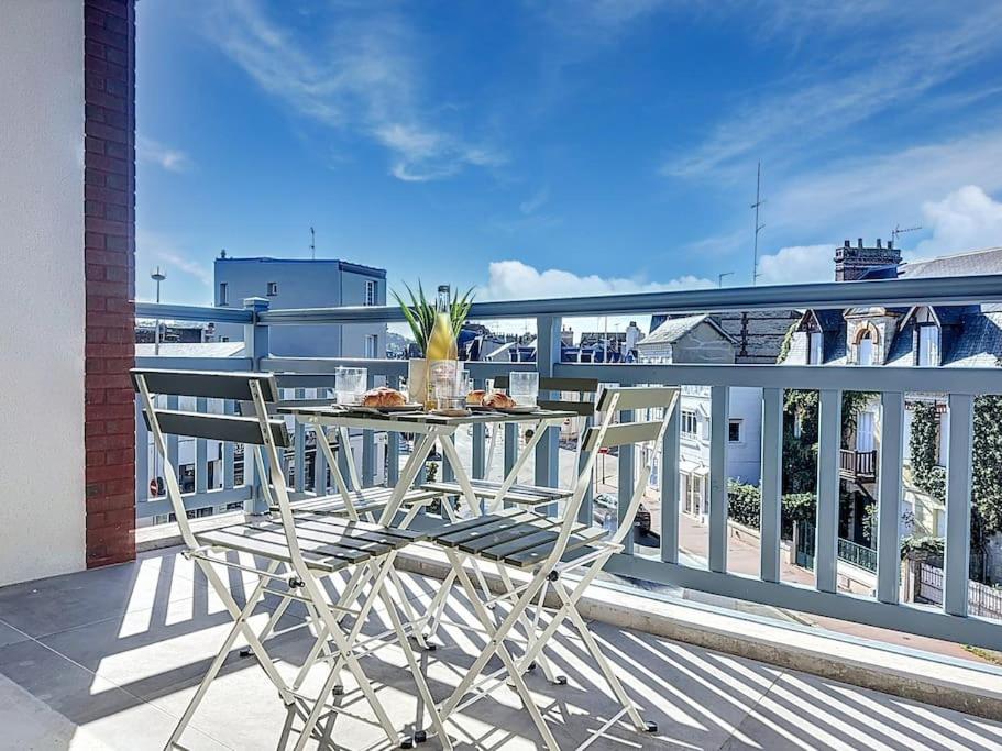 une table et des chaises assises sur un balcon dans l'établissement Le Royal YourHostHelper, à Deauville