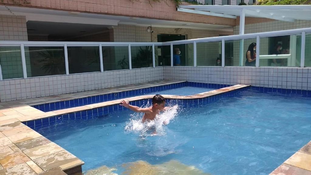 a young boy is in a swimming pool at Apê Temporada II Praia Grande SP Completo com Piscina, Churrasqueira, Estacionamento in Praia Grande