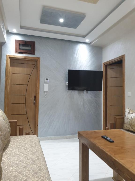 - un salon avec un mur, une télévision et une table dans l'établissement Résidence MIMOUNA FAMILY, à Tanger
