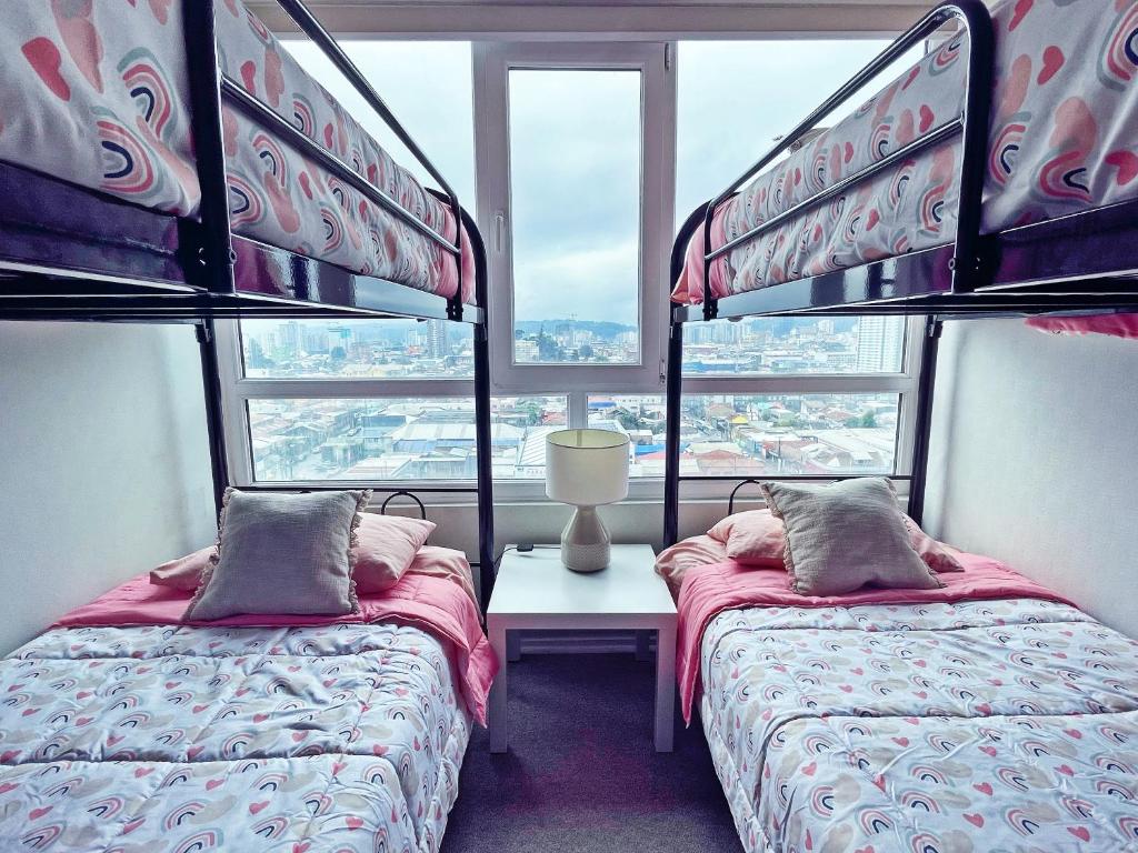 two beds in a room with two windows at Departamento céntrico, acogedor y bien equipado in Concepción
