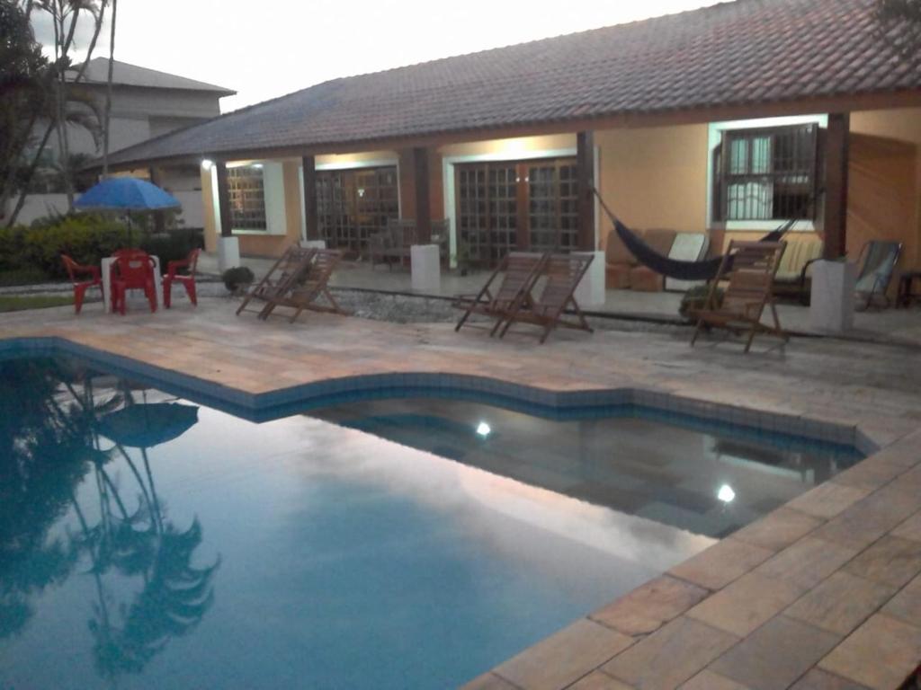 ペルイベにあるRecanto Praia Peruibeの椅子と家のあるプール