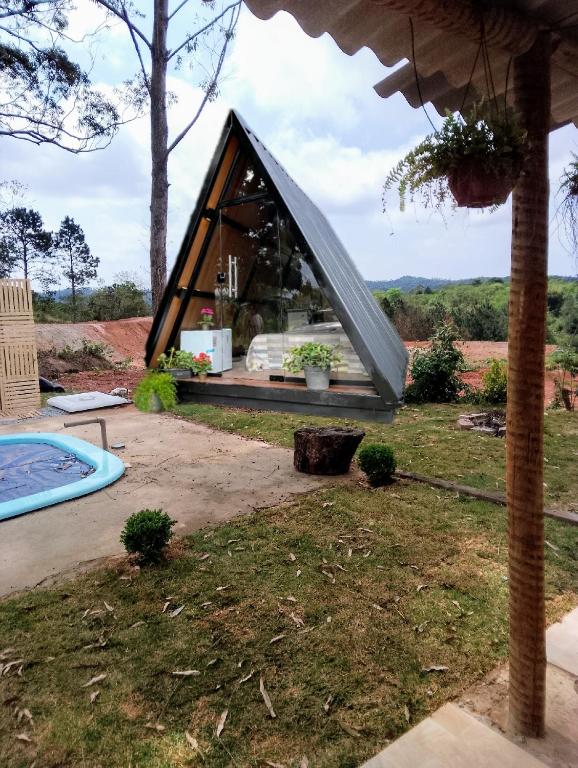 ein dreieckiges Haus mit einem Fenster in einem Hof in der Unterkunft Chalé chacara dos eucaliptos in Itapecerica da Serra